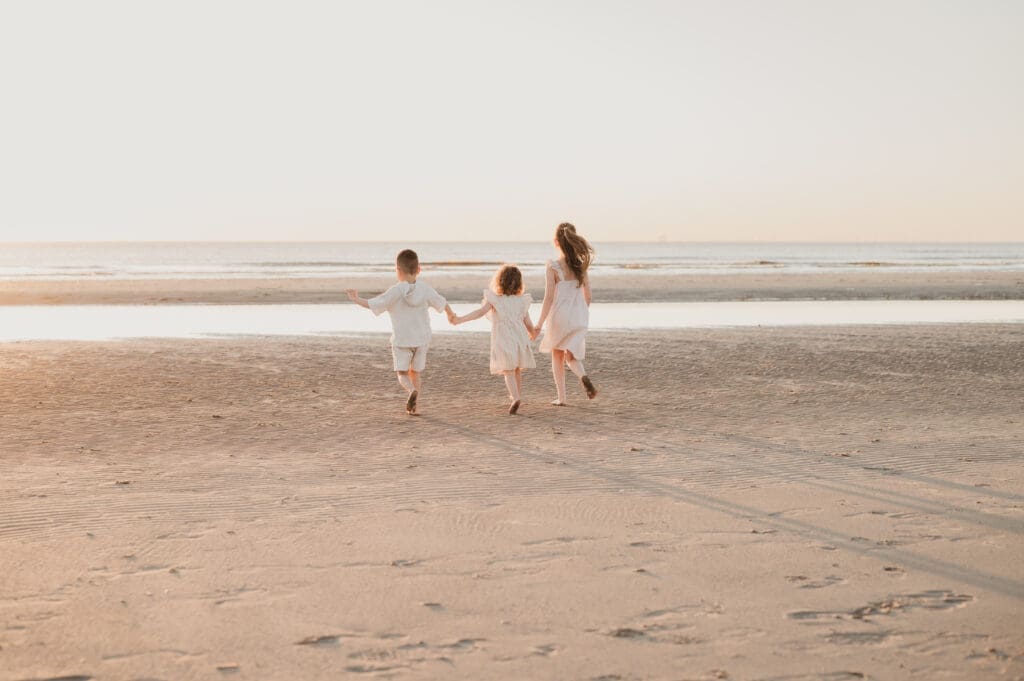 Kinderen spelen in de zee tijdens een fotoshoot in Wijk aan Zee bij zonsondergang in het gouden uur.