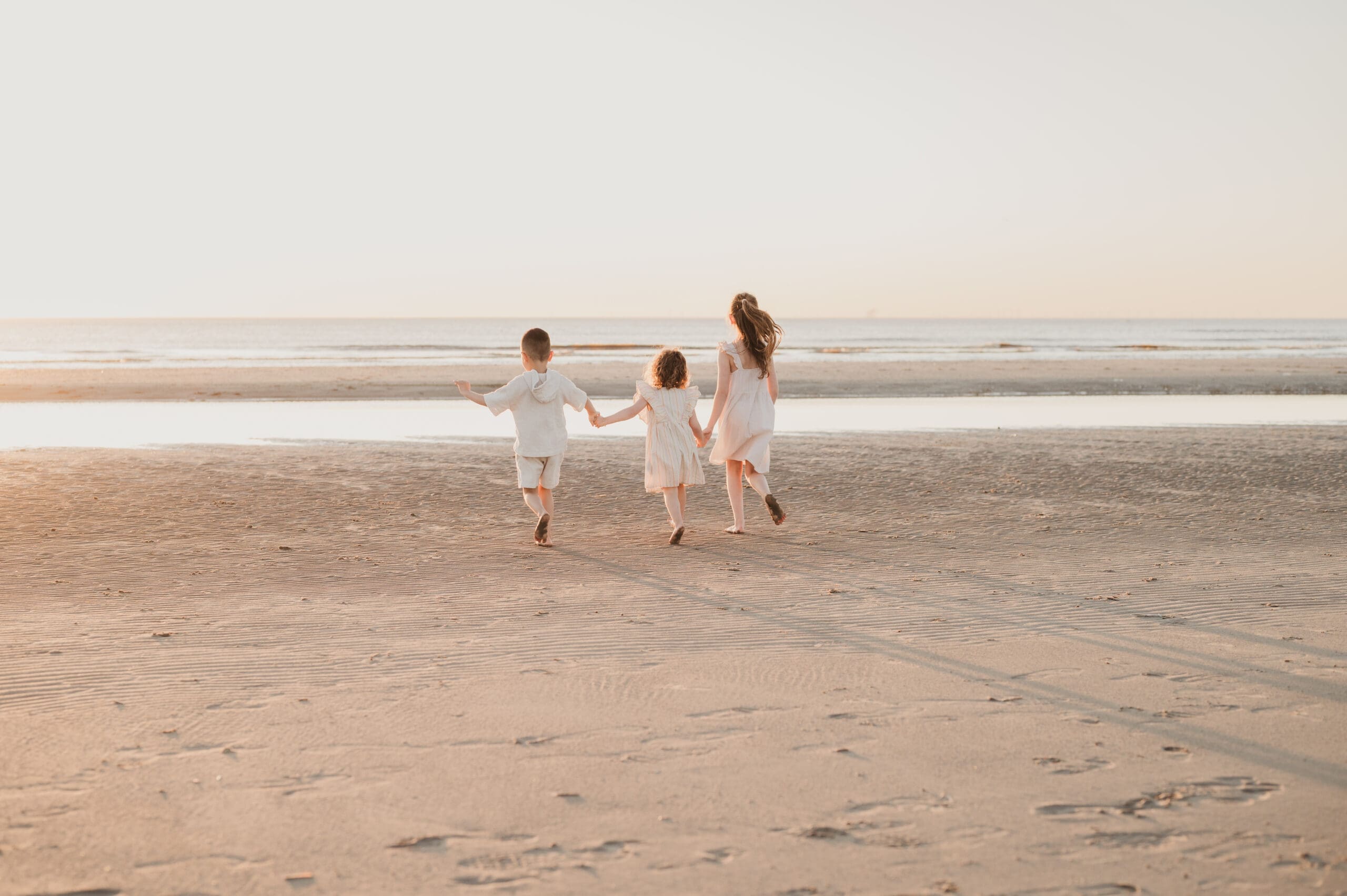 Kinderen spelen in de zee tijdens een fotoshoot in Wijk aan Zee bij zonsondergang in het gouden uur.